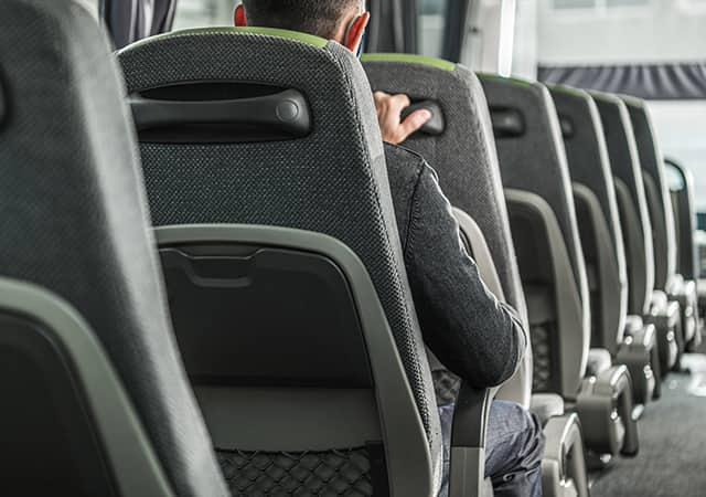 Interior of a bus rental with a passenger sitting in a seat facing away